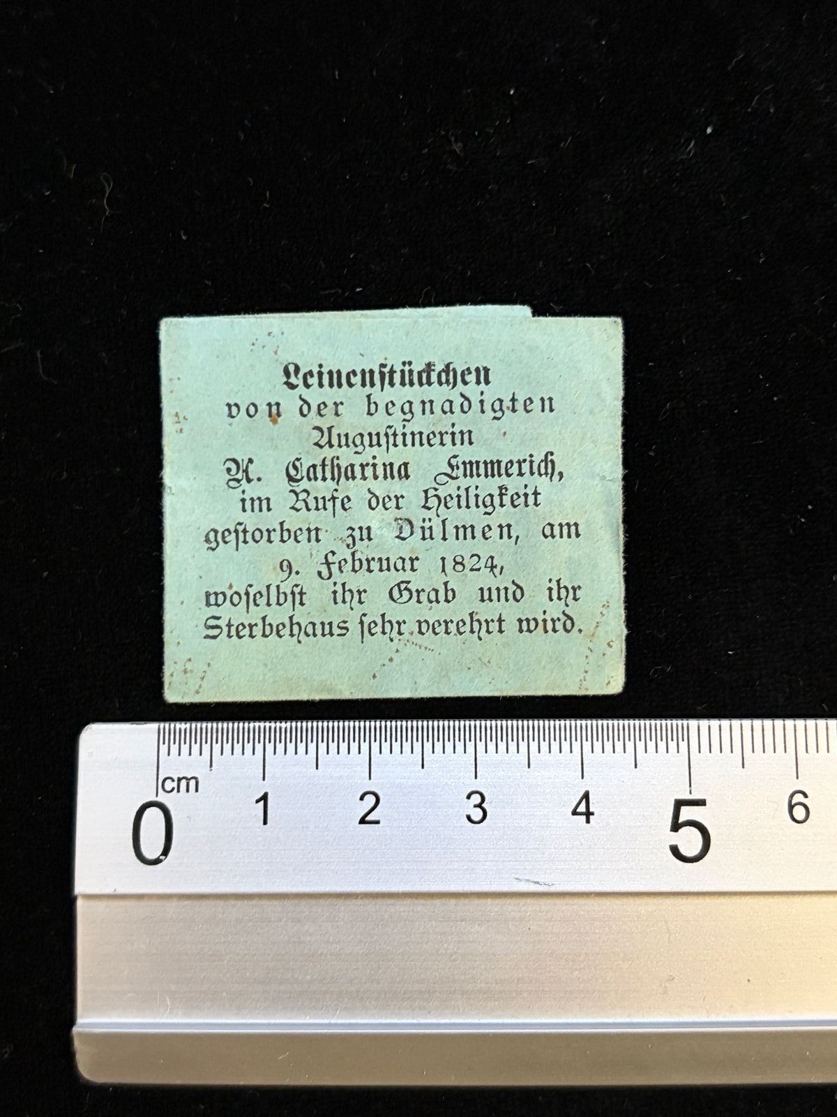 Anne Catherine Emmerich relic packet next to a ruler showing its size, about 4.3 x 3.5 cm