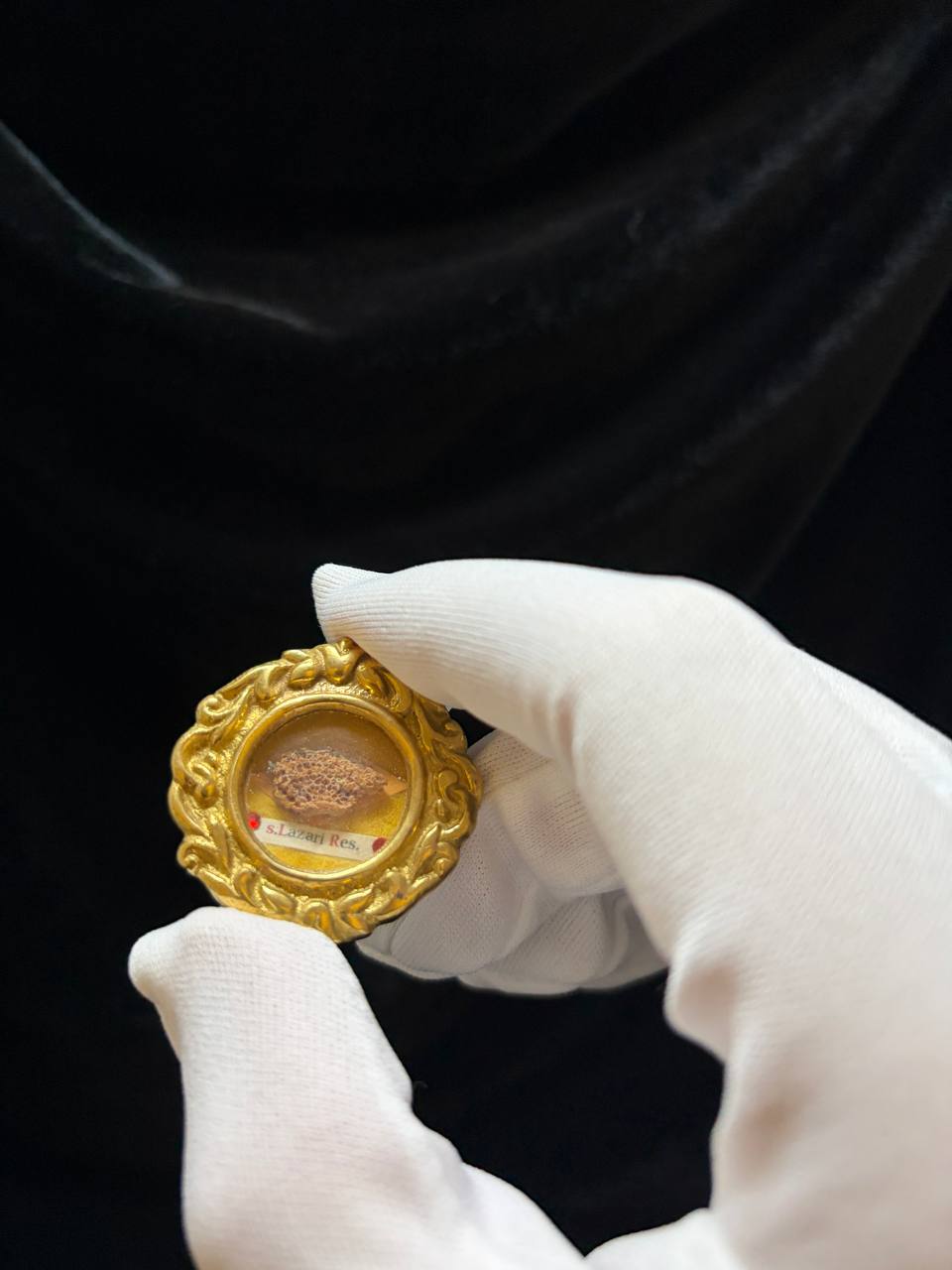 Saint Lazarus of Bethany relic in an ornate gilt theca, label S. Lazari Ep., held in a white glove