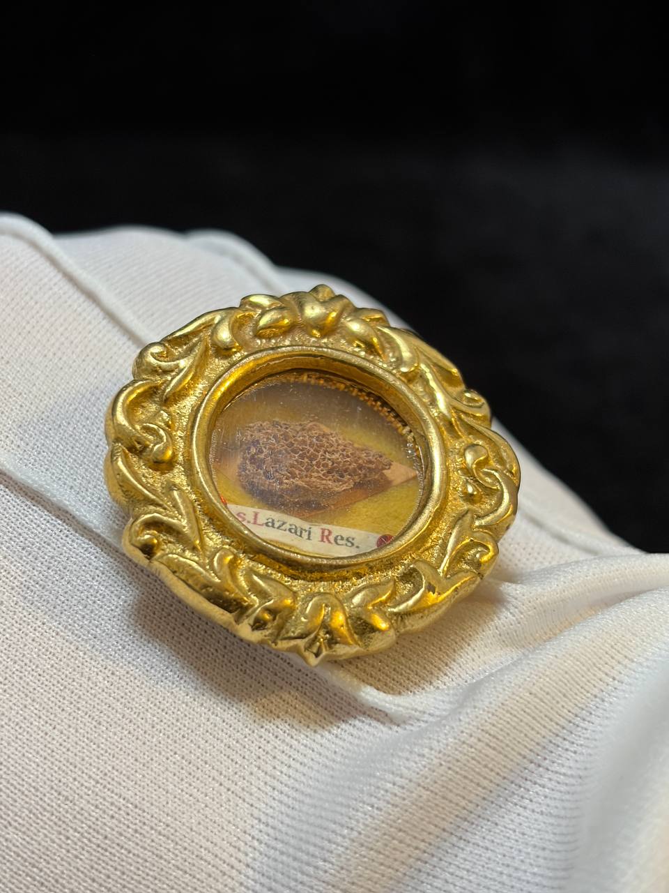 Saint Lazarus of Bethany relic in an ornate gilt theca, label S. Lazari Ep., on a white glove, angled view