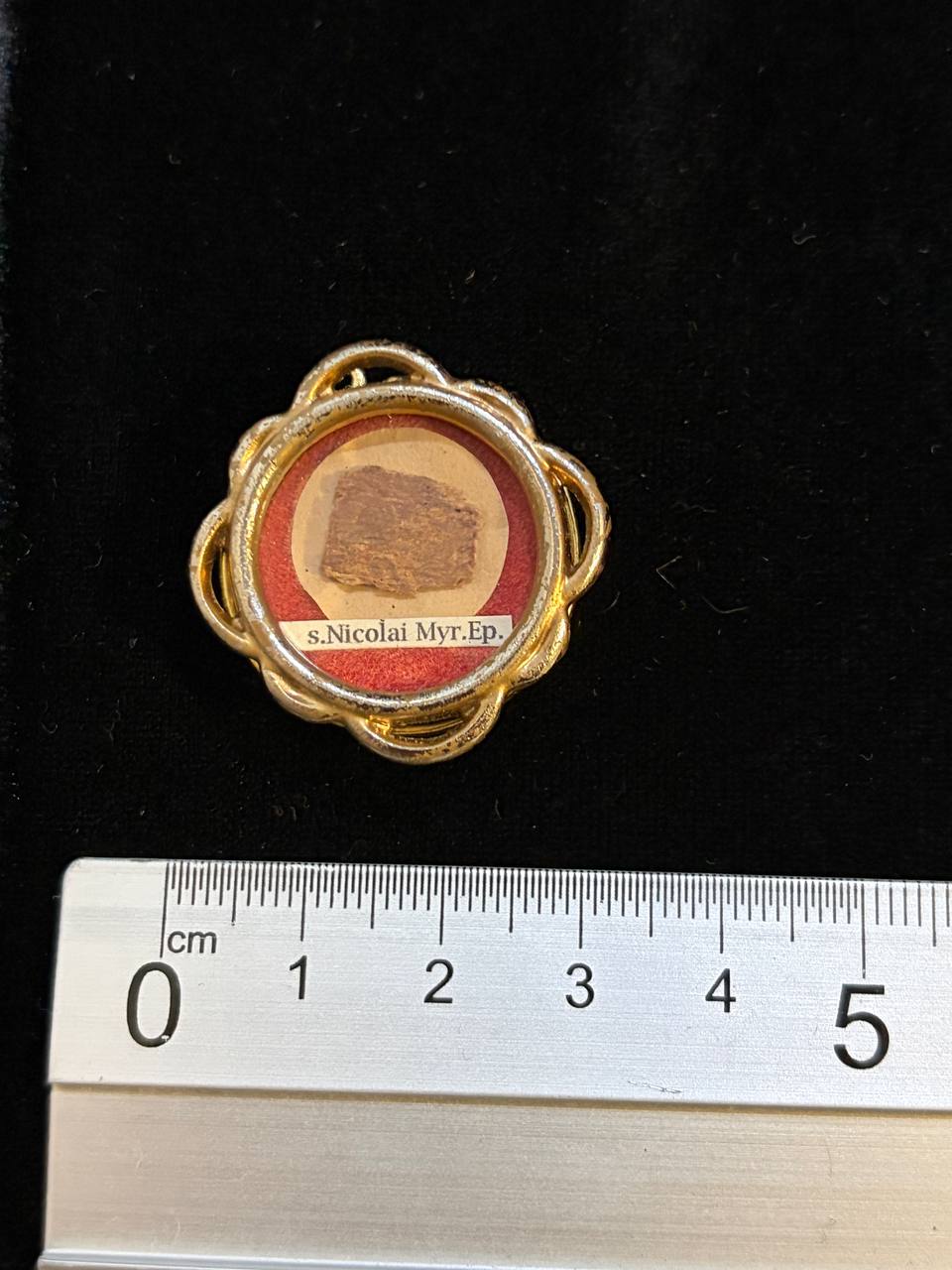Saint Nicholas of Myra relic theca next to a ruler, about 3.5 cm across