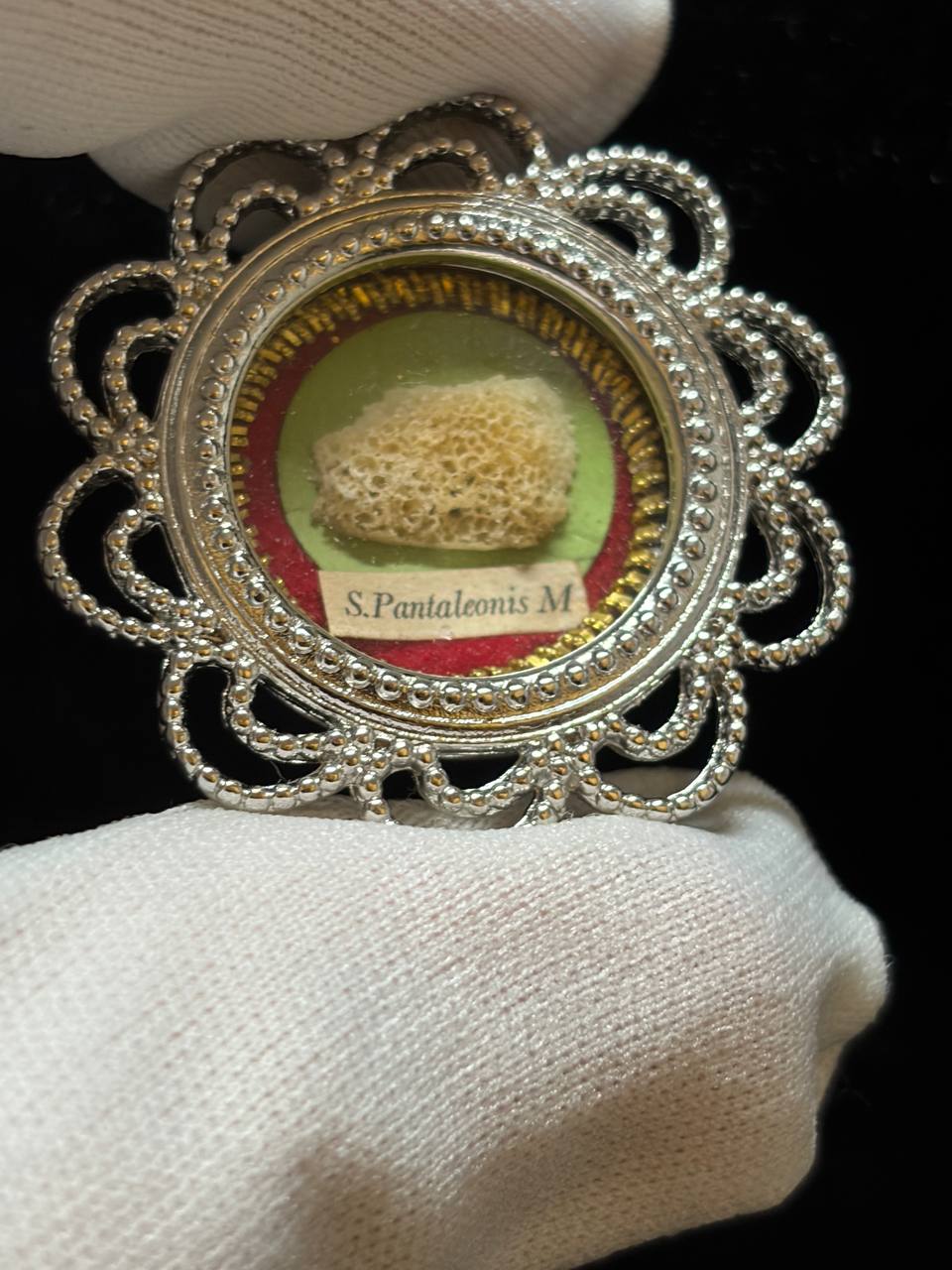 Saint Pantaleon relic in a silver filigree theca, label S. Pantaleonis M., held in a white glove, detail