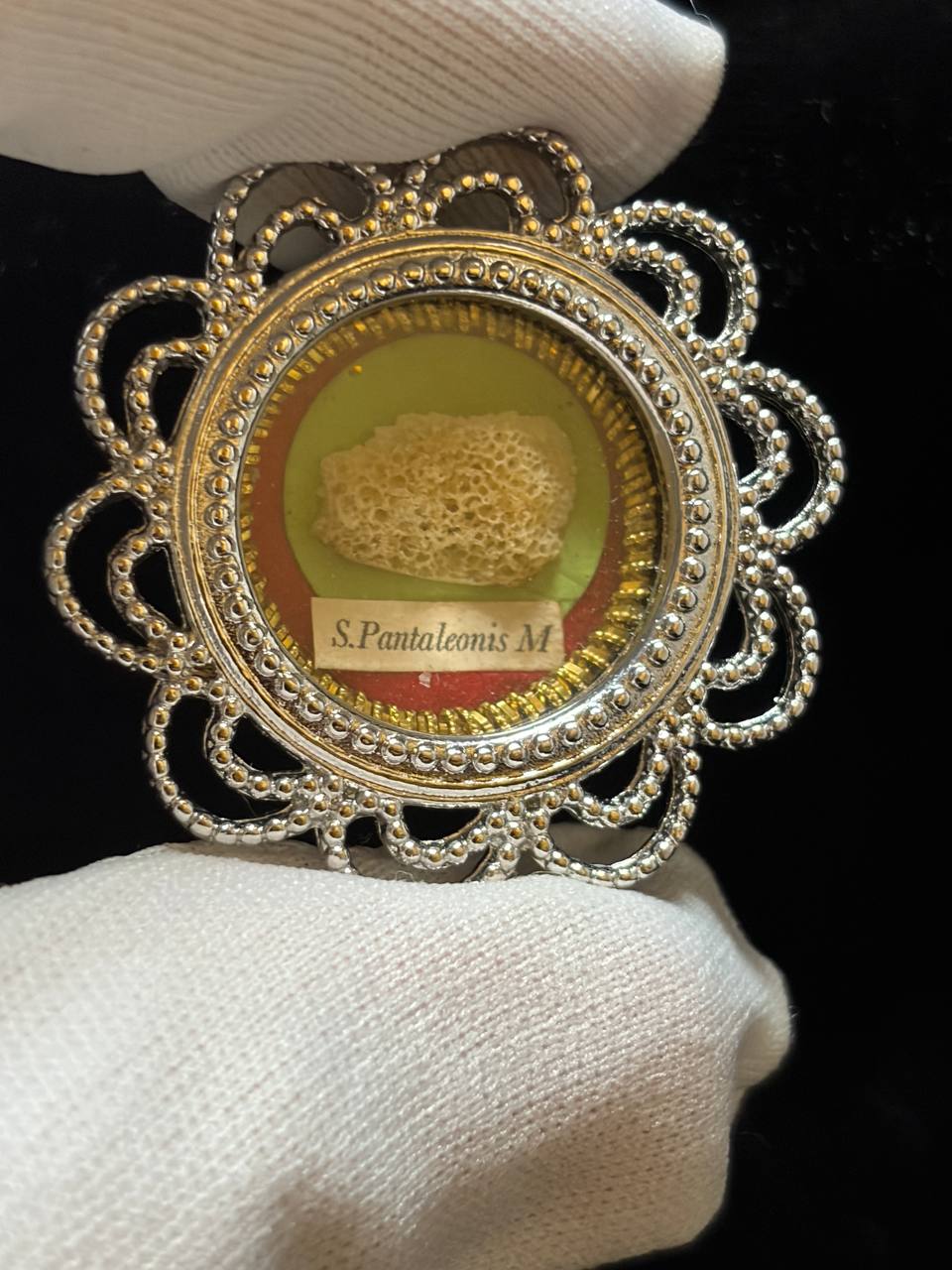 Saint Pantaleon relic in a silver filigree theca, label S. Pantaleonis M., held in a white glove