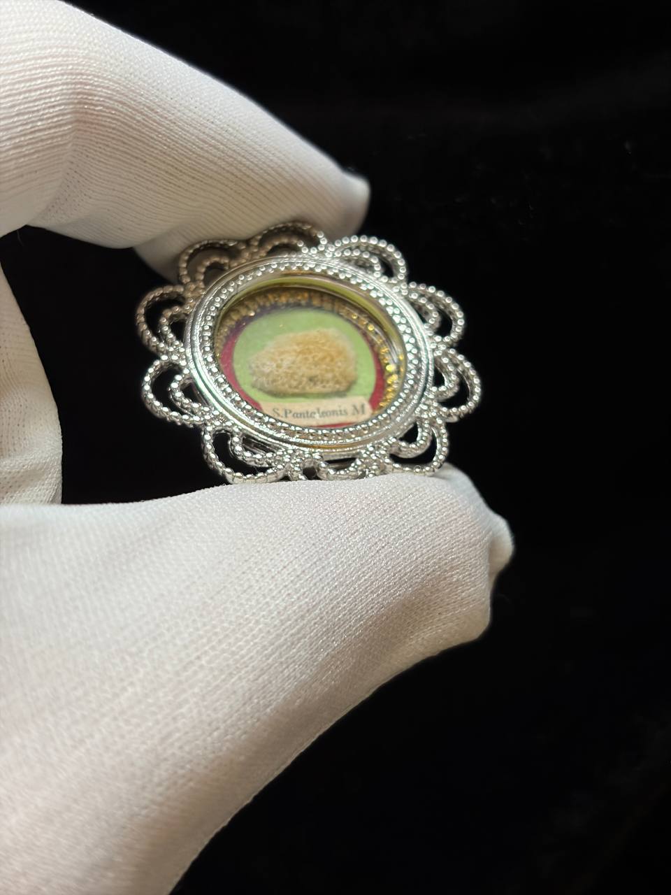 Saint Pantaleon relic in a silver filigree theca, label S. Pantaleonis M., held in a white glove, side view