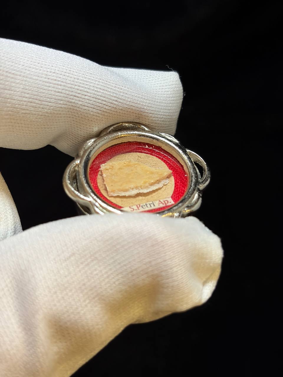 Saint Peter the Apostle relic in a silver quatrefoil theca, label S. Petri Ap., held in a white glove, side view