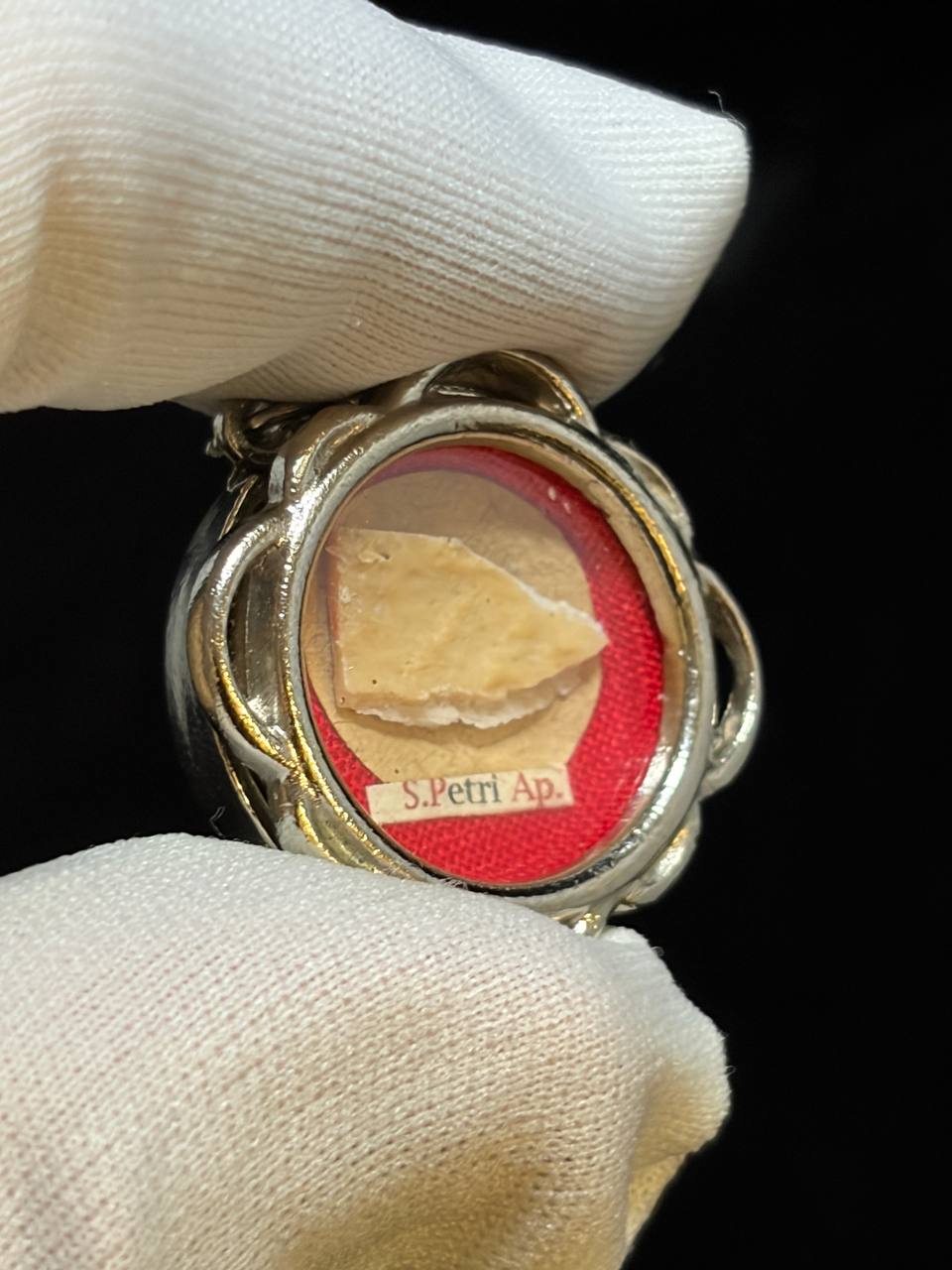 Saint Peter the Apostle relic in a silver quatrefoil theca, label S. Petri Ap., held in a white glove, detail