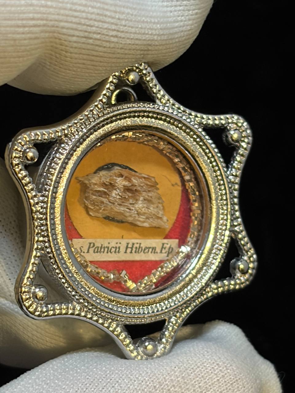 Saint Patrick of Ireland relic in a silver star-shaped theca, label S. Patricii Hiben. Ep., held in a white glove