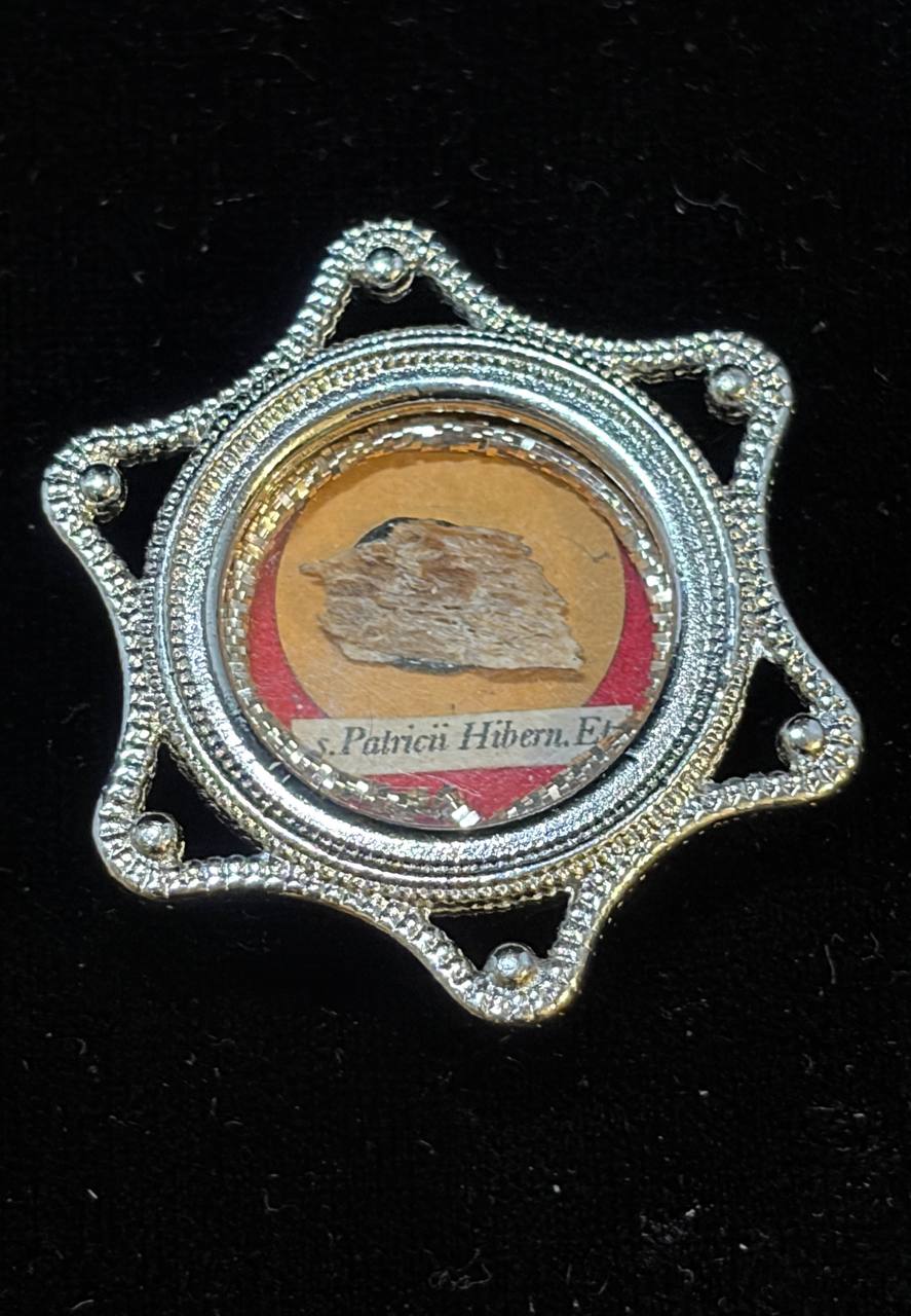 Saint Patrick of Ireland relic in a silver star-shaped theca, label S. Patricii Hiben. Ep., front view on black velvet
