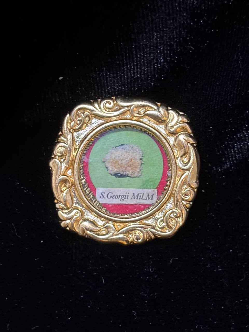 Saint George the Martyr relic in an ornate gilt scroll-frame theca, label S. Georgii M., on black velvet
