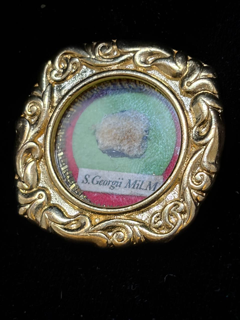 Saint George the Martyr relic in an ornate gilt scroll-frame theca, label S. Georgii M., close-up of the bone relic