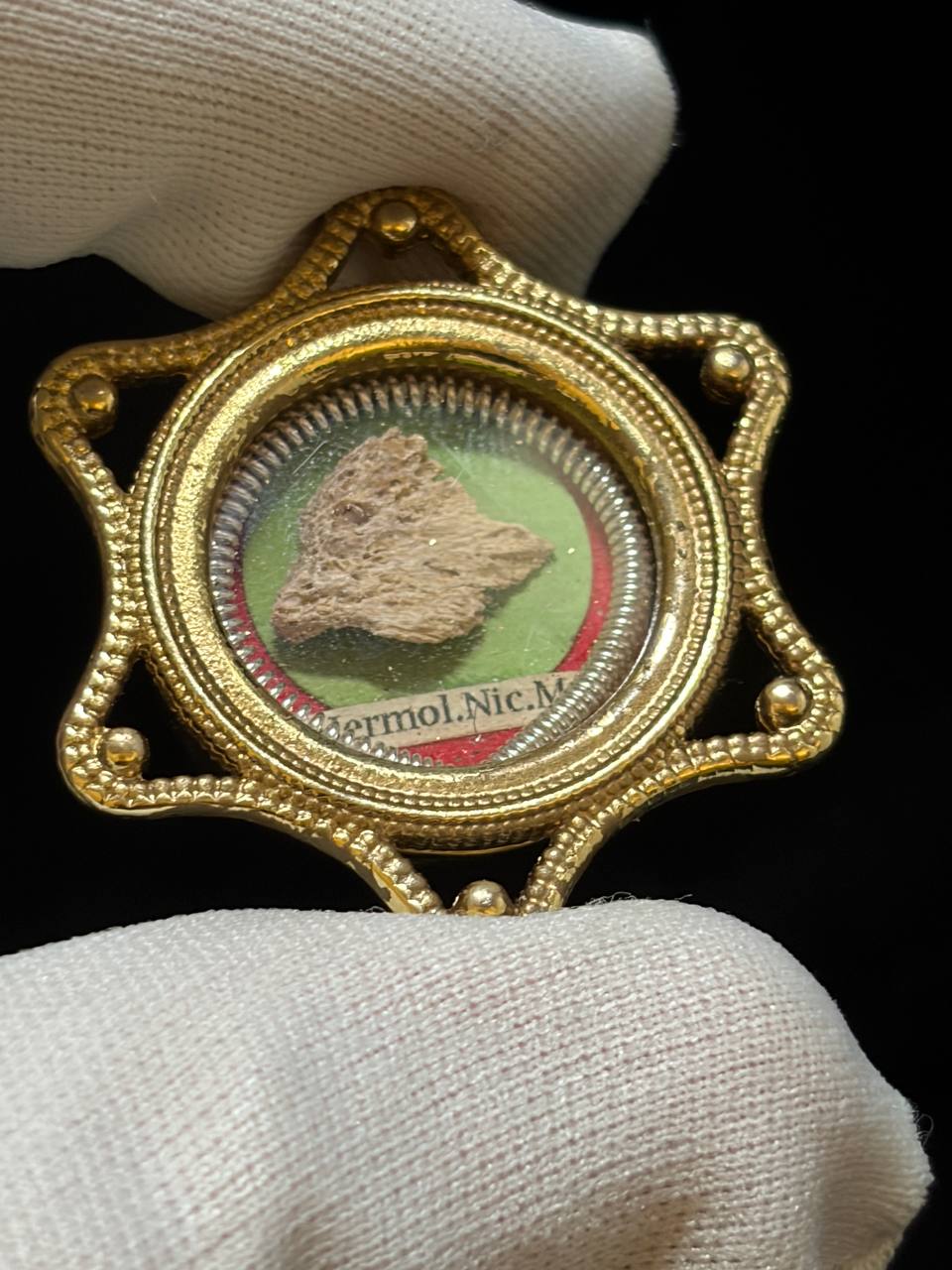 Gilt star-shaped theca with Saint Hermolaus relic held between gloved fingers