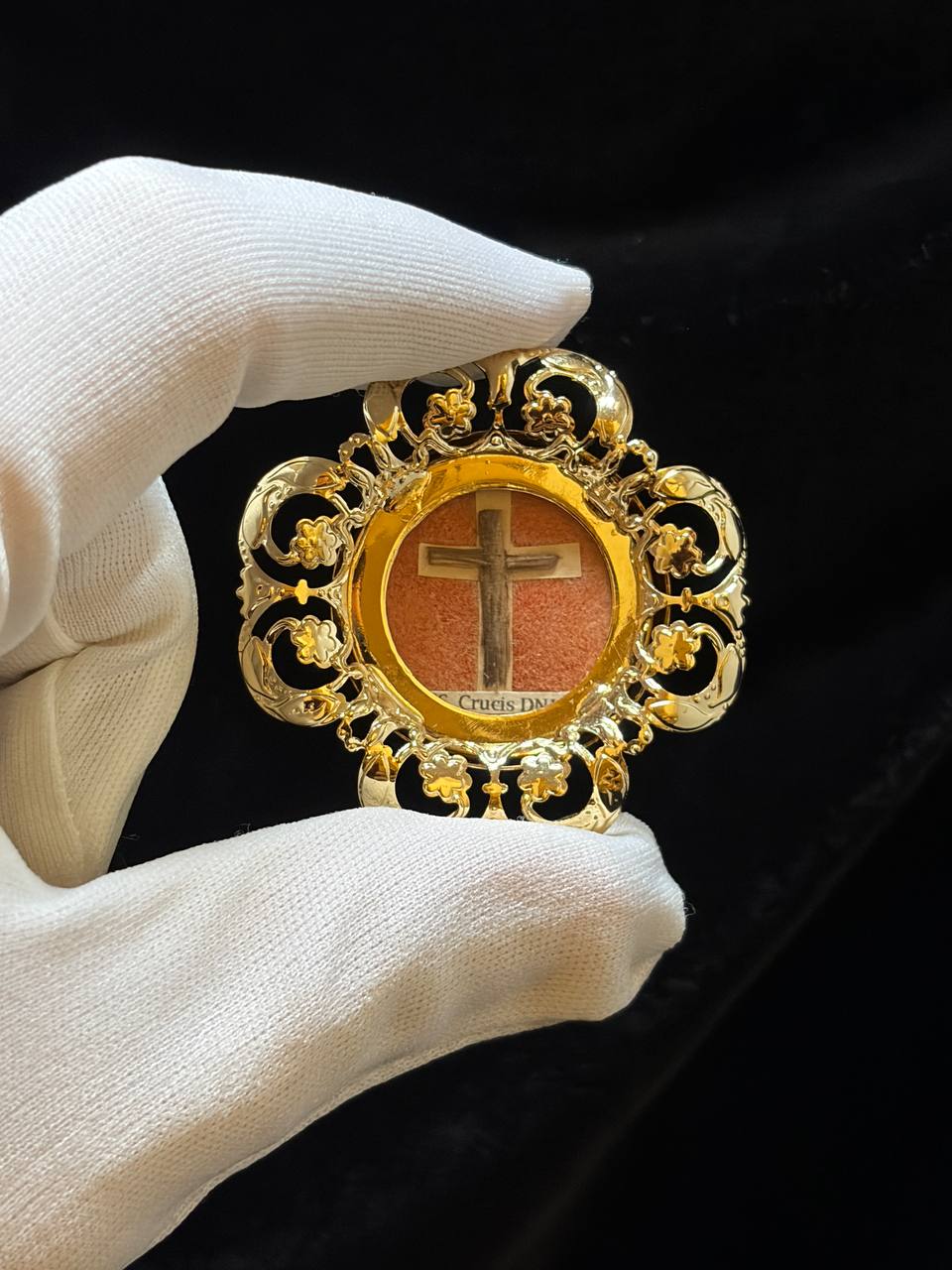 True Cross relic theca held in a white glove, gilt back visible