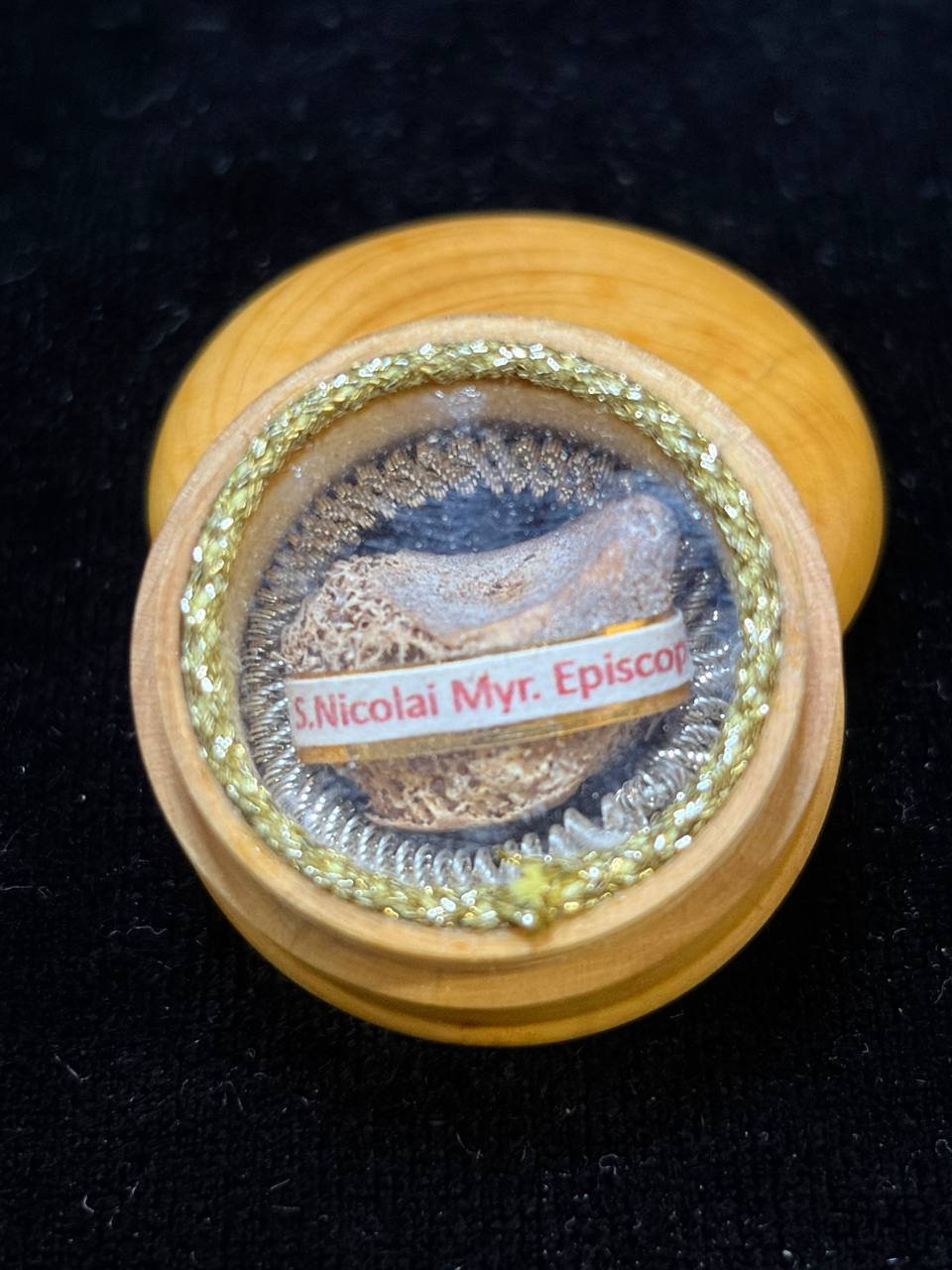Saint Nicholas of Myra relic ex phalange digiti in a round wooden theca with gilt trim, label S. Nicolai Myr. Episcopi