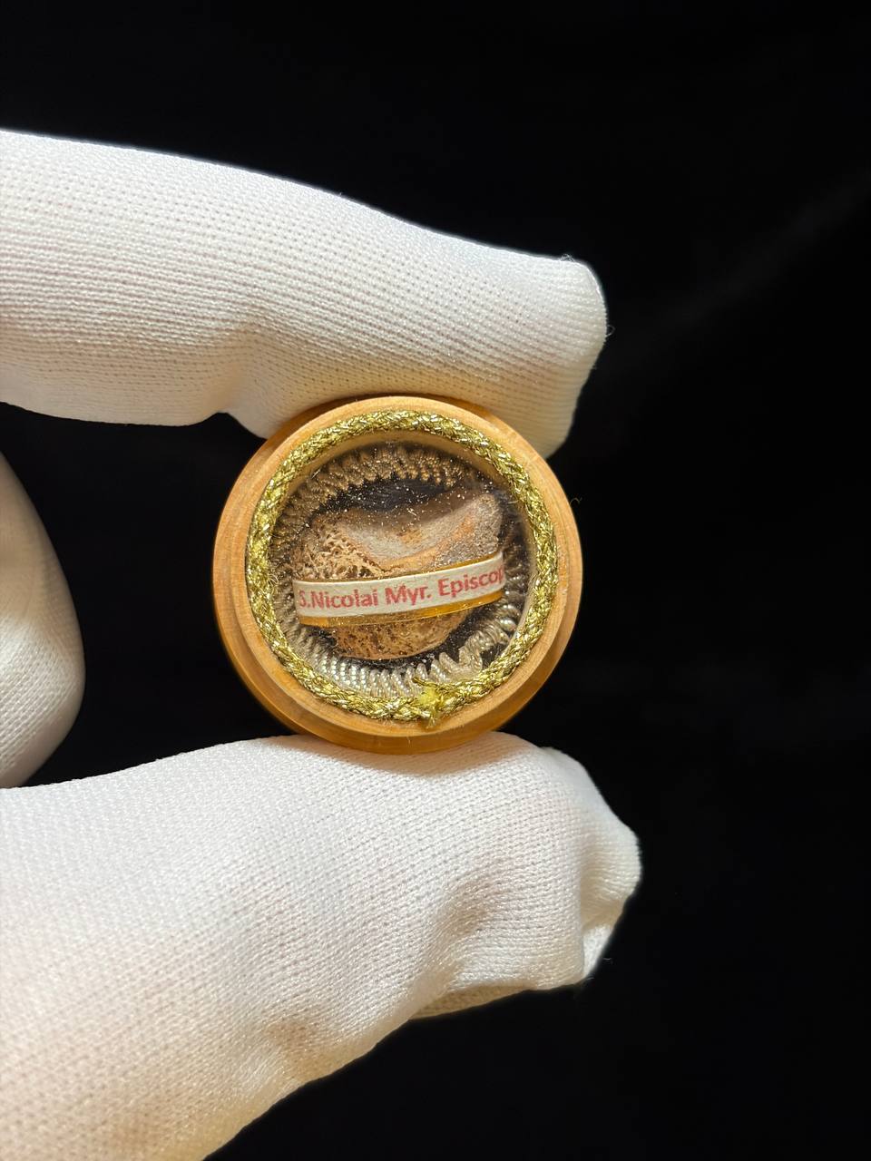 Saint Nicholas of Myra relic theca held between gloved fingers