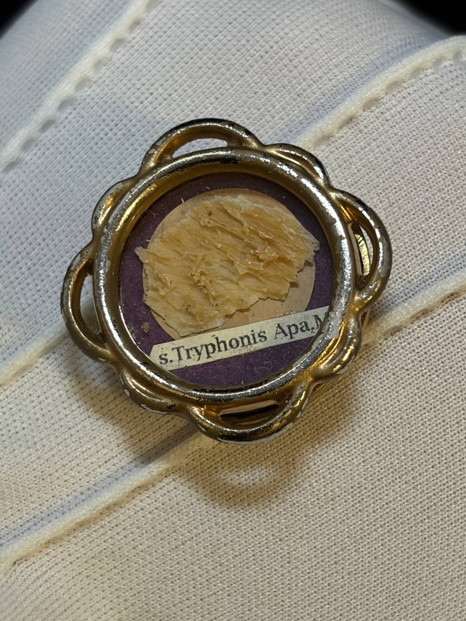 Close-up of the Saint Tryphon relic fragment on purple silk inside the gilt theca