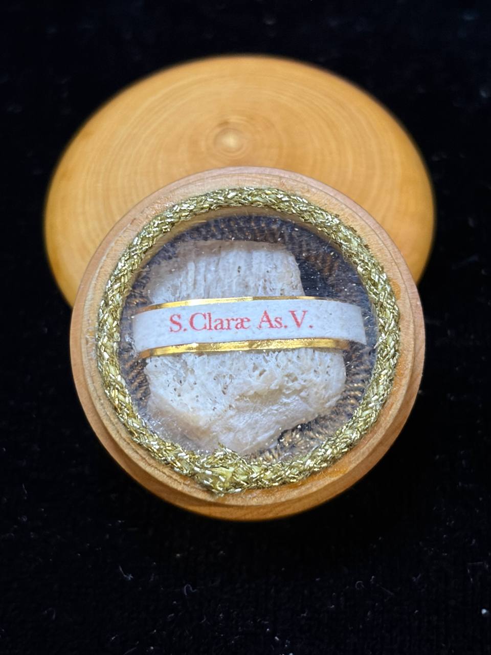 Saint Clare of Assisi relic in a round wooden theca with gilt trim and label S. Clarae As. V.