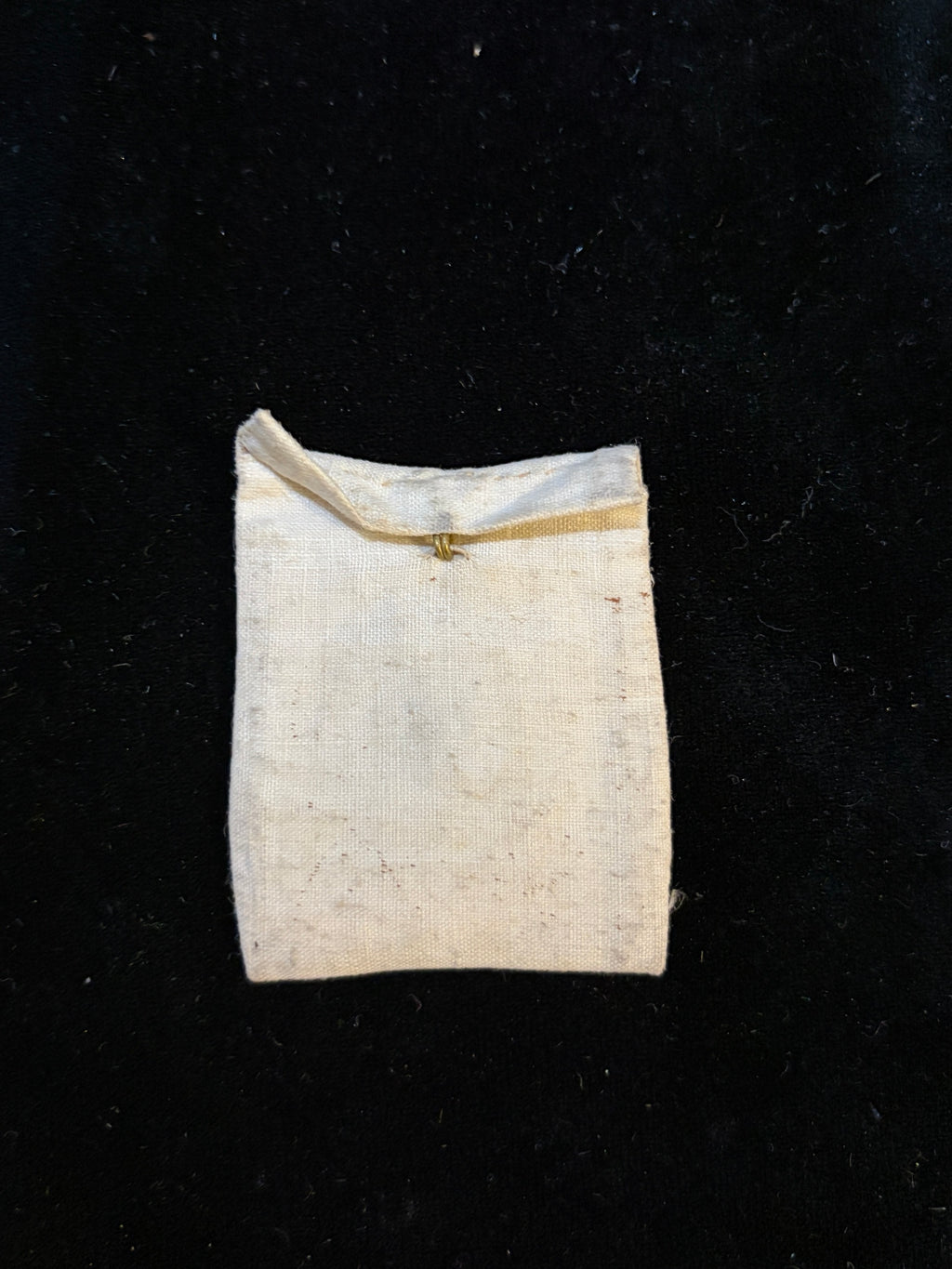 Linen relic bursa closed with its flap and original brass hook for pinning to clothing
