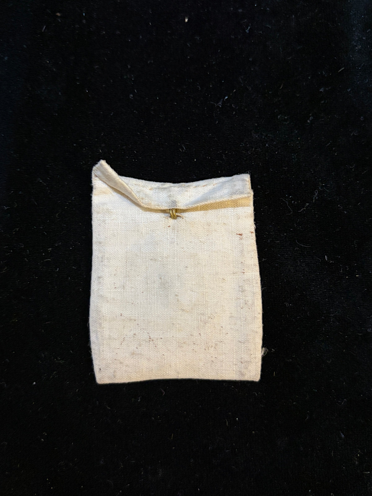 Linen relic bursa closed with its flap and original brass hook for pinning to clothing