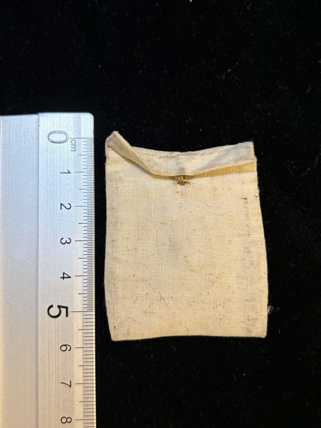 Saint Clement relic bursa next to a ruler showing its size, about 4.6 x 5.8 cm